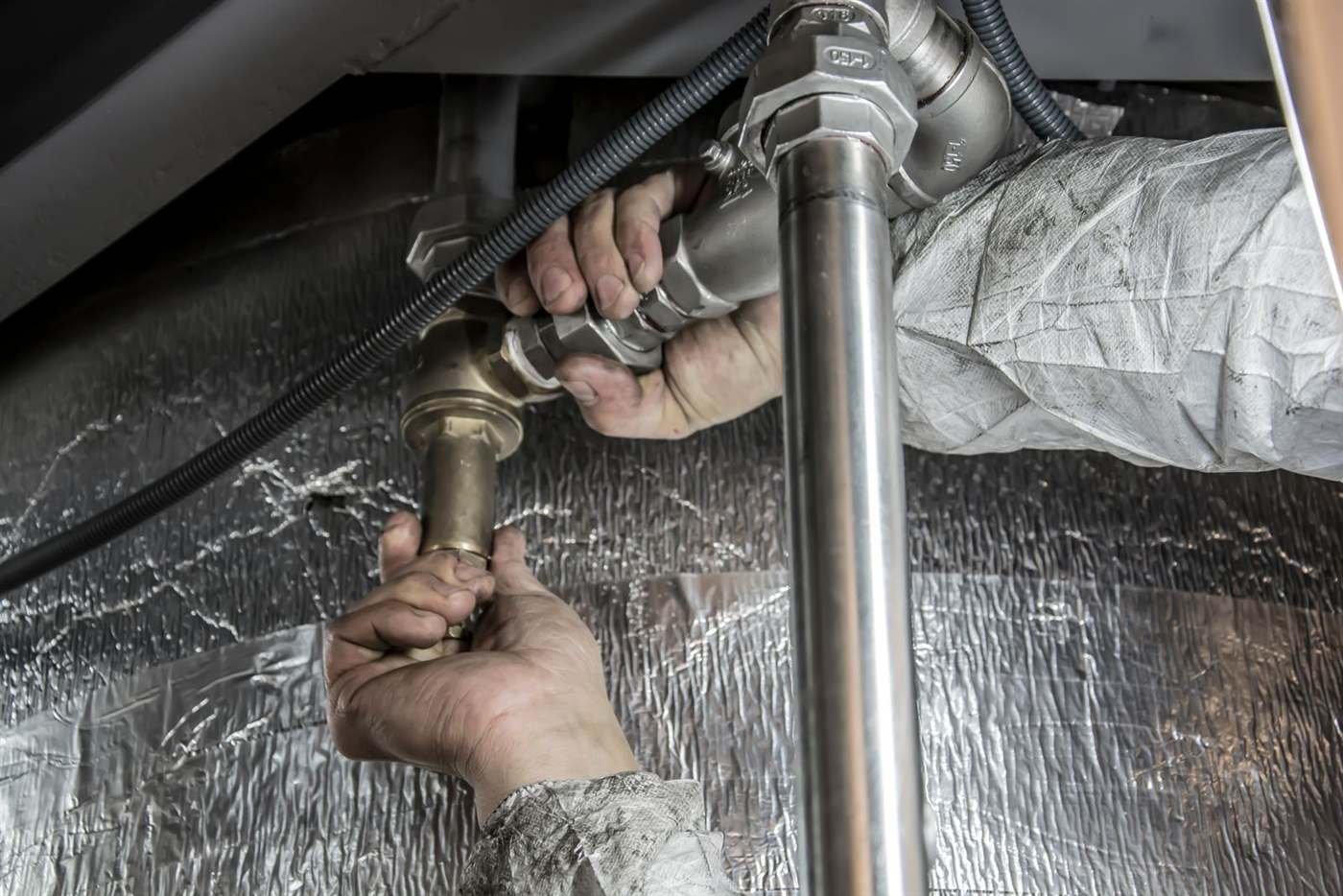 Plumber making an emergency pipe repair under a kitchen sink in Chicago